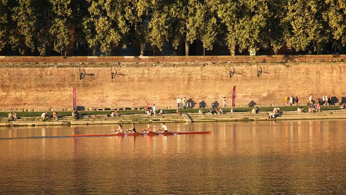 Quai de brique au bord de la Garonne à Toulouse, promeneurs et rameurs sous les platanes